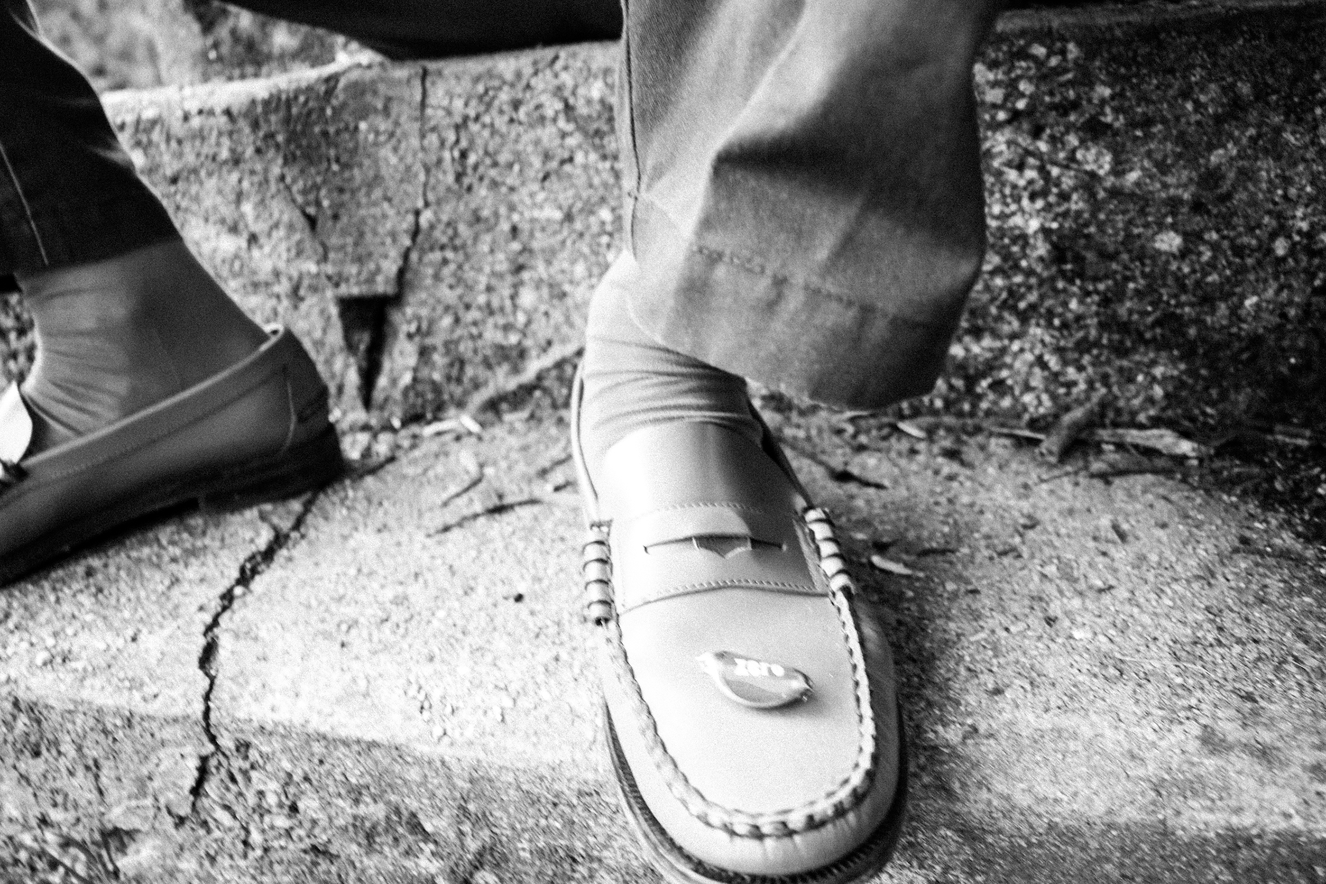 Details — pink socks, blue loafers, cracked concrete.